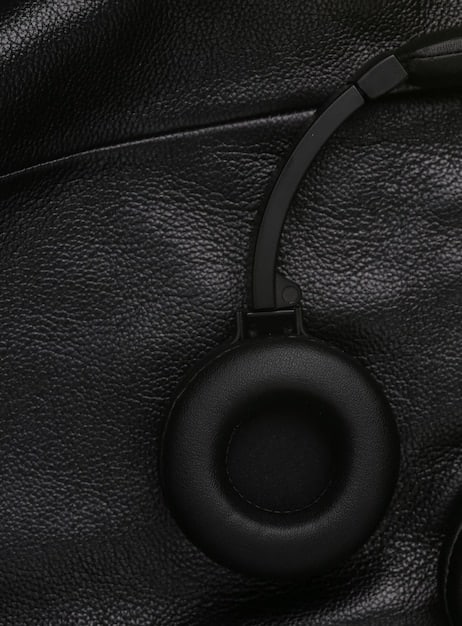 A close-up shot of the earcups of a modern noise-canceling headphone, highlighting the premium materials like soft leather and brushed metal, with subtle tech details.