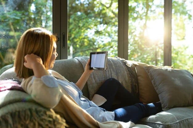 The tablet is being held and used comfortably on a couch, emphasizing its lightweight and portable nature for casual use and content consumption.