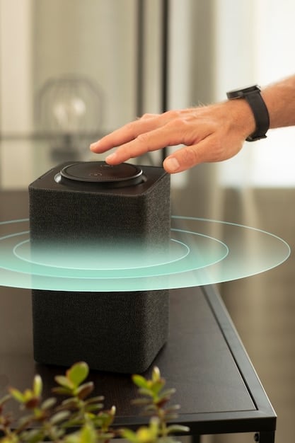 A person's hand reaching towards a Bluetooth speaker (e.g., Anker Soundcore Flare) that is placed near a campfire at dusk, with subtle smoke and ember glow around the speaker, highlighting its suitability for evening outdoor gatherings.