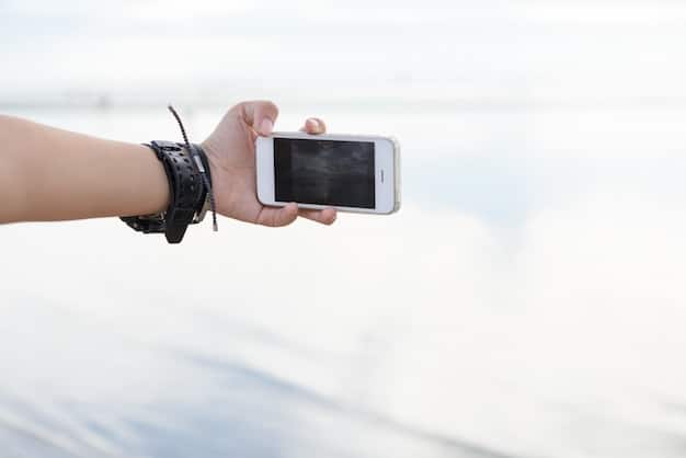A person's hand holding a smartphone, wirelessly connected to an action camera, displaying the camera's live 4K video feed and control interface on the phone screen, emphasizing seamless user experience and app control.